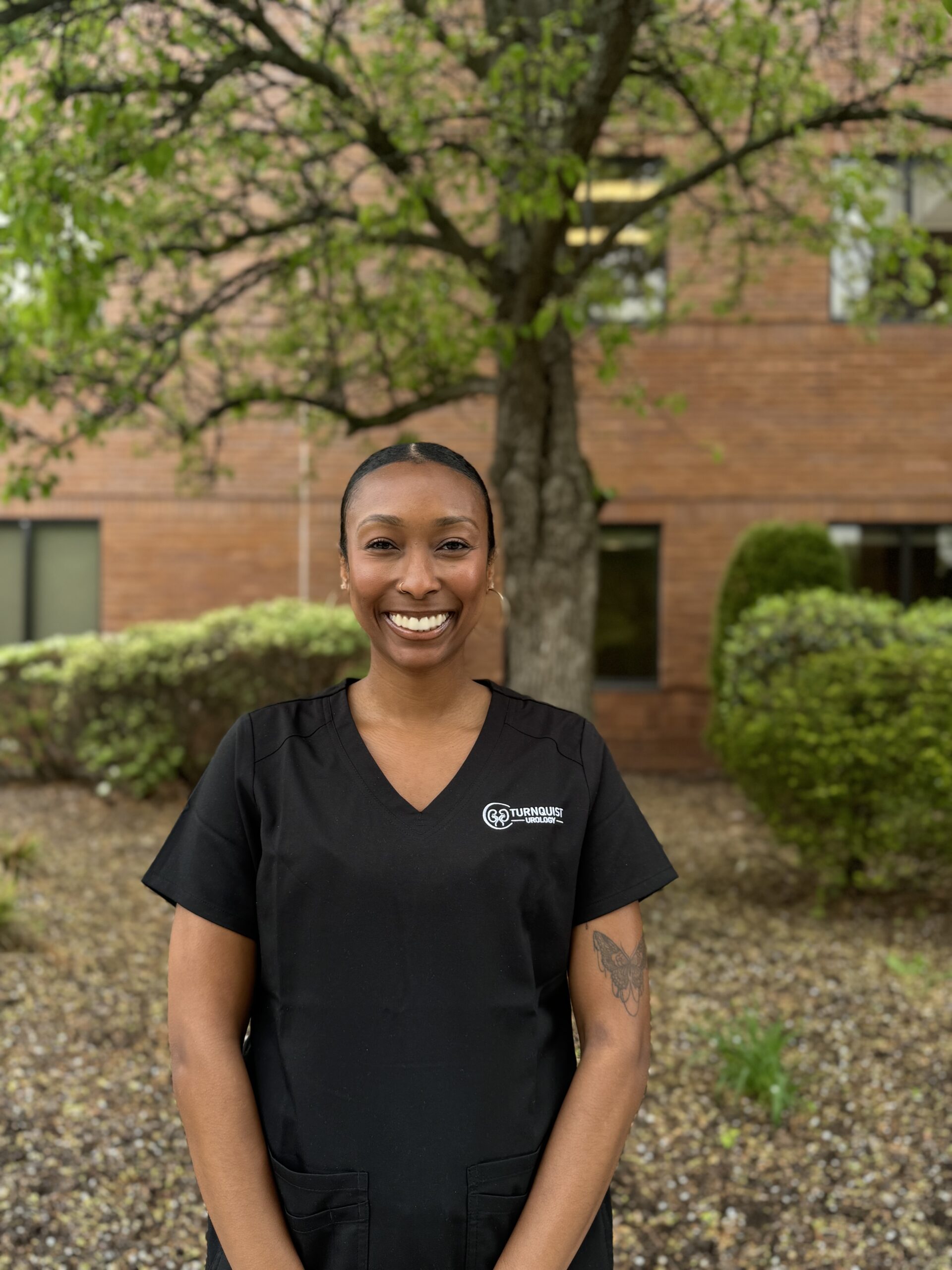 Smiling nurse outdoors with greenery background