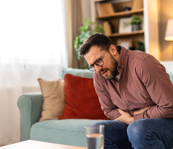 Man experiencing stomach pain on sofa