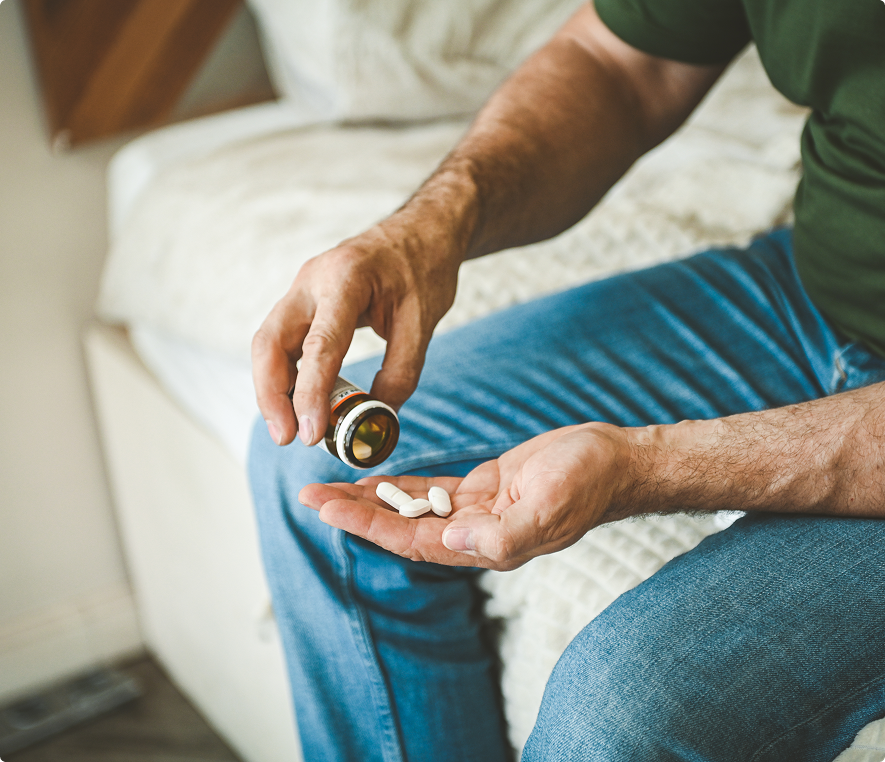 Man holding pills on bed