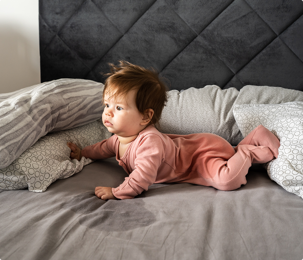 Baby in pink pajamas on bed